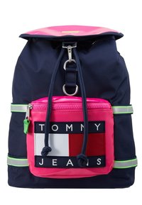 Sac à dos bleu marine avec dessus et poche avant roses, comportant un patch logo Tommy Jeans et des bandes réfléchissantes vertes sur les côtés.