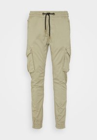 Beiga cargobyxor med elastisk midja, dragsko, två sidofickor och elastiska muddar. Tillverkade av mjukt, slitstarkt tyg.