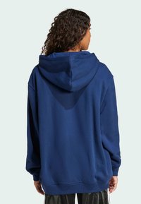 Marinblå oversized hoodie i mjukt material, med justerbar huva och ribbade muddar. Enkel design utan synliga mönster eller logotyper.