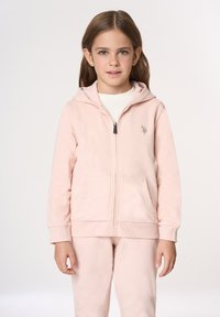 Felpa con cappuccio rosa chiaro con cerniera, realizzata in tessuto morbido, dotata di cappuccio, tasche frontali e un piccolo logo sul petto a sinistra.