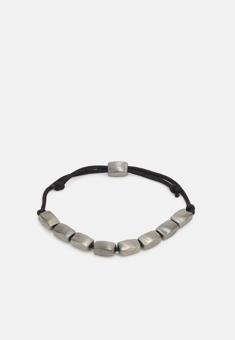 Bracelet à cordon noir réglable avec neuf perles rectangulaires argentées mates et un fermoir central argenté.