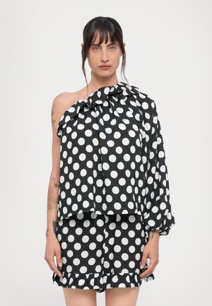 Zwart-witte polka dot off-the-shoulder top met een gerimpelde halslijn, gecombineerd met bijpassende shorts met een gerimpelde zoom. Lichtgewicht stof.