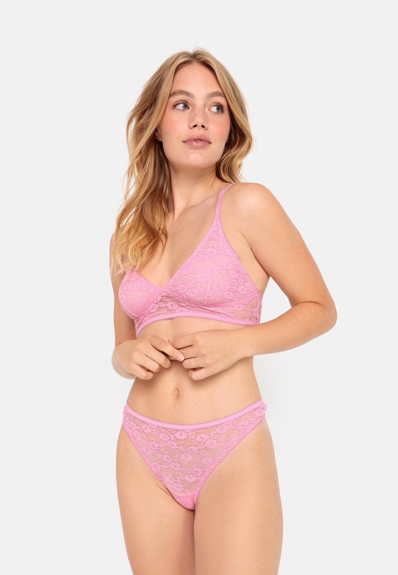 Růžový krajkový bralette a odpovídající tanga s květinovým vzorem, průhlednými částmi, nastavovacími ramínky a vlnitým lemem pro zvýraznění detailu.