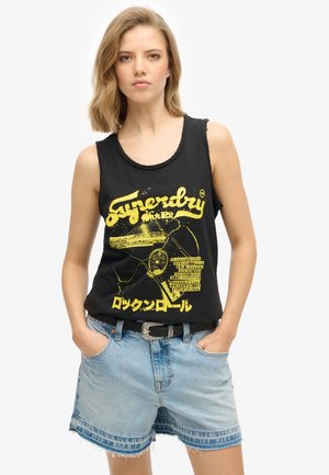 Top nero senza maniche con stampa grafica gialla, realizzato in morbido tessuto di cotone. Abbinato a pantaloncini in denim, che mostrano una vestibilità comoda e un orlo sfrangiato.