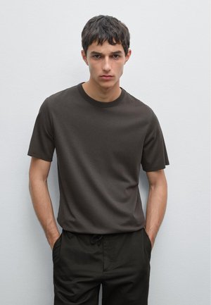 Dunkelbraunes kurzärmliges T-Shirt aus glattem Baumwollstoff. Verfügt über einen runden Halsausschnitt und eine lockere Passform. Kombiniert mit dunklen Hosen.