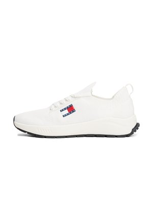 Baskets basses blanches avec dessus en maille, lacets, semelle noire et logo Tommy Jeans sur le côté.