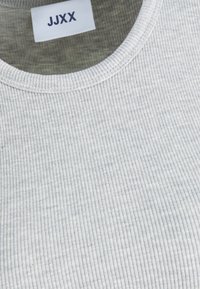Szürke bordázott textil kerek nyakú kivitelben. A galléron látható a "JJXX" címke. Az anyag lágy és texturált.