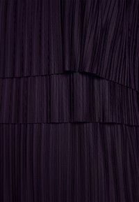 Lila plisserad klänning med texturerade vertikala linjer och lager, som visar en slät tyggdesign med en subtil lyster.
