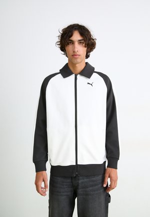 Black and white zip-up jacket with a collared neckline, featuring a smooth fabric, ribbed cuffs, and a small logo on the left chest.