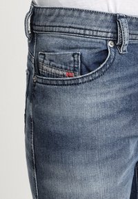 Denimjeans i medelblå tvätt med avsmalnande passform. Har fem fickor, kontrasterande sömnad och en liten logotyp i sidfickan.