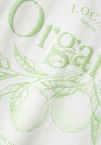 Witte stof met een gestructureerde groene print met daarop biologische sinaasappels, bladeren en het woord "Biologisch" in grote, glinsterende letters.