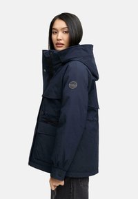 Marineblauwe, gewatteerde jacket met een capuchon, rits en drukknopen, voorzien van een klepzak en een ronde logo op de bovenkant van de mouw. Geweven stof.