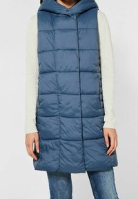 Vadderad marinblå väst med luva, med en quiltad design, framknäppning och sidofickor. Tillverkad av lätt, slät tyg.