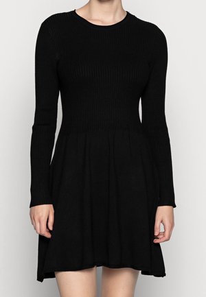 Zwart geribbeld jurk met lange mouwen en een aansluitend lijfje, uitlopend bij de taille naar een uitlopende rok. Glad textuur en een klassieke halslijn.
