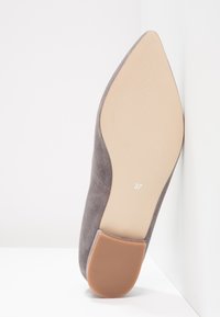 Grå mocka högklackad sko med spetsig tå, med en texturerad beige sula och en storleksetikett som visar 37.