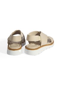 Beige sandalen met een glad leren bovenwerk, verstelbare band en witte rubberen zool met een lichte plateau en een gestructureerde voetbed.