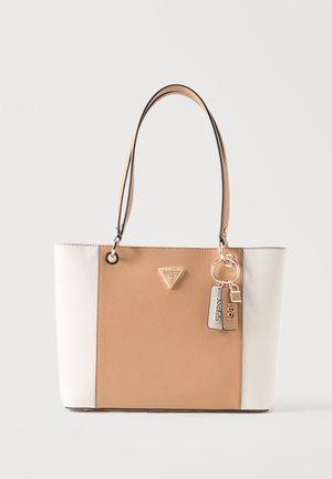 Tofarvet beige og hvid håndtaske med dobbelte håndtag, Guess-logo i guldton og nøgleringstags med "Guess" og "1981" detaljer.