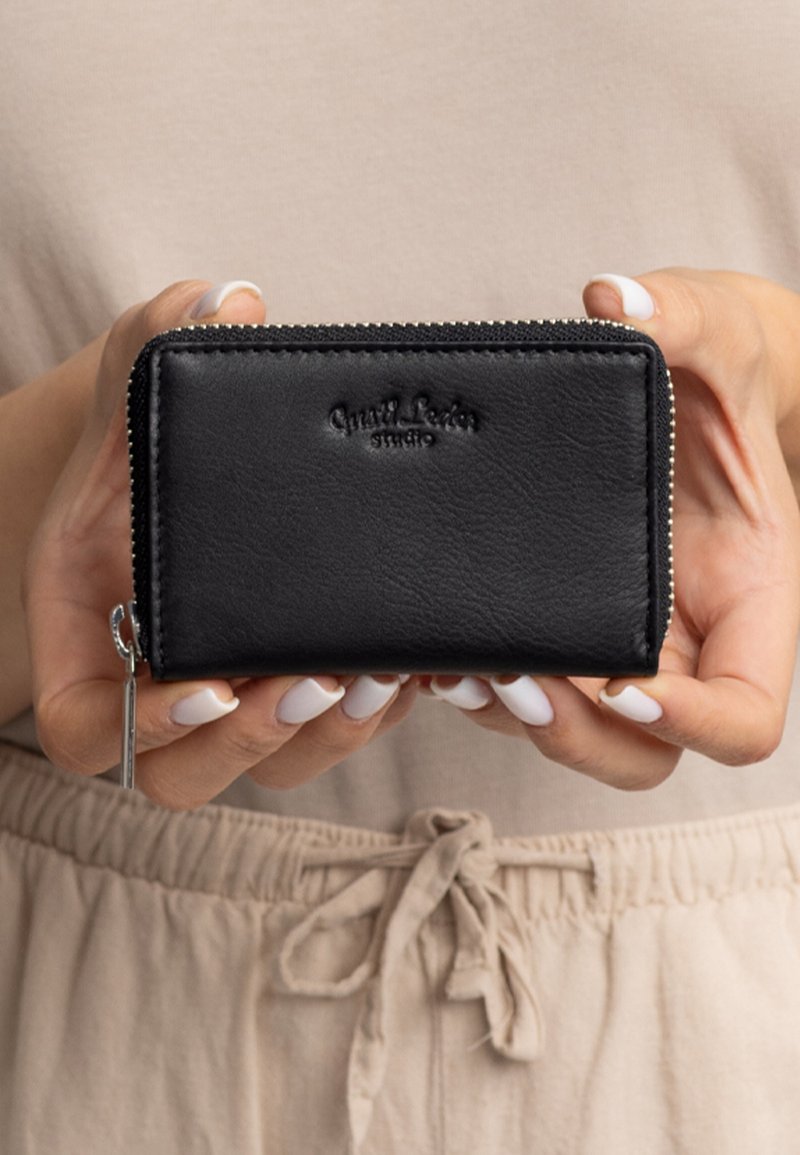 Schwarze Lederbörse mit strukturiertem Finish, ausgestattet mit einem Reißverschluss, geprägtem Logo auf der Vorderseite und einem Reißverschlusszug mit Silberverzierung.