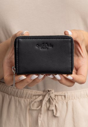 Portefeuille en cuir noir avec une finition texteurée, doté d'une fermeture éclair, d'un logo en relief sur le devant et d'une tirette en métal argenté.