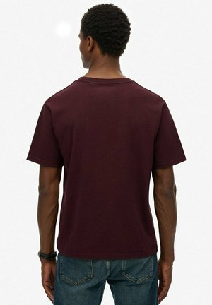 Burgundowa koszulka z krótkim rękawem, wykonana z bawełny, z okrągłym dekoltem i luźnym krojem. Widok z tyłu ukazuje gładką fakturę bez wzorów.
