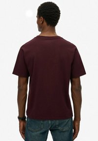 Bordeaux kortekorte t-shirt van katoen, met een ronde hals en een ontspannen pasvorm. De achterkant laat een gladde textuur zonder patronen zien.