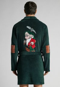 Zielona flanelowa szlafrok z haftowanym motywem postaci krasnoluda na plecach, brązowymi łaty na łokciach i paskiem do wiązania. Miękka tekstura.