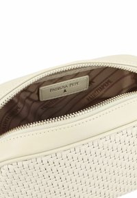 Crème geweven leren tas met een gestructureerd oppervlak, voorzien van een zilveren ritssluiting en een gevoerd interieur met een logo-label.