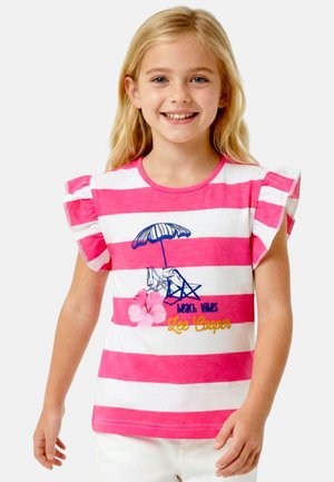 Fille souriante aux longs cheveux blonds portant un t-shirt à rayures roses et blanches avec une scène de plage et des manches volantées.