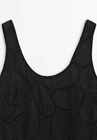 Haut noir sans manches avec encolure dégagée présentant un motif en dentelle ajourée ovale irrégulier sur toute la surface du tissu.