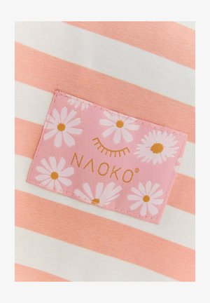 Pruhovaná látka v ružovej a bielej farbe s ružovou nášivkou s bielymi sedmikráskami a textom "NAOKO" v zlatej farbe. Hladká, ľahká textúra.