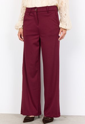 Burgundy wide-leg trousers made from soft fabric, featuring front pockets and a button closure, paired with dark brown pointed shoes.
