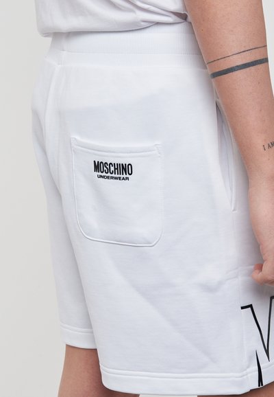 Shorts bianchi in cotone con una tasca posteriore su cui è stampato "MOSCHINO UNDERWEAR" in nero. Il design include una stampa sul lato e una vita a costine.