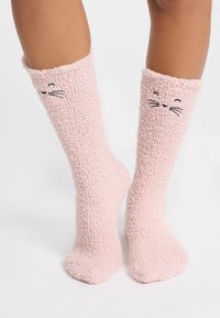 Calzini rosa soffici con una finitura testurizzata, caratterizzati da un delicato motivo di faccia di gatto, cuciture nere per i baffi e una comoda fascia elastica.