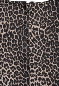 Luipaardprint stof met een beige achtergrond en zwarte vlekken, voorzien van een rits aan de achterkant en een gestructureerd oppervlak.