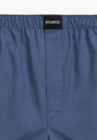 Niebieskie kąpielówki z elastycznego materiału z elastycznym pasem. Z tyłu znajduje się czarna metka z napisem "ATLANTIC" w kolorze białym.