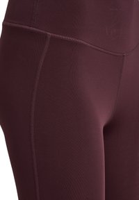 Bourgognefarvede leggings med høj talje lavet af strækbart materiale med flade sømme og en glat tekstur. Har en diskret logo på linningen.