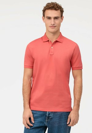 Polo en coton lisse couleur corail, avec un col et des manches courtes. Le polo a un léger brillant et une coupe classique.