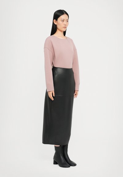 Helles rosa Sweatshirt mit überschnittenen Schultern, kombiniert mit einem schwarzen Leder-Midirock. Schwarze Stiefeletten runden das Outfit ab. Glatte Texturen und strukturierte Designs.