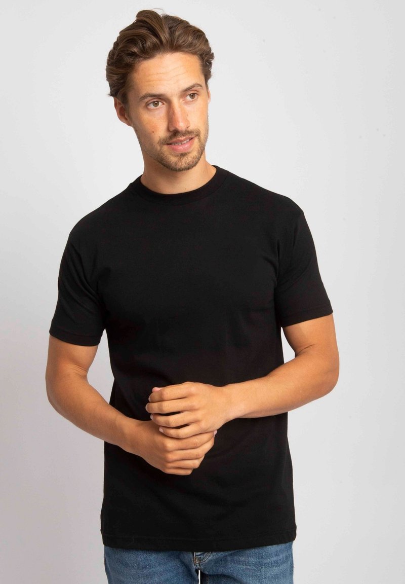 Zwarte katoenen t-shirt met korte mouwen en een klassieke ronde halslijn, met een reguliere pasvorm en een soepele textuur. Gecombineerd met blauwe jeans.