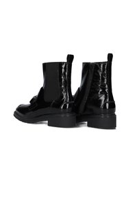 Black patent leather ankle boots with elastic side panels, textured back, block heel, and a decorative strap detail on the front.