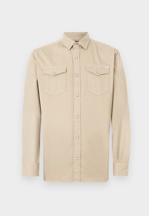 Beige langermet skjorte med krage og to knapped lomme på brystet, vist på en plain hvit bakgrunn.