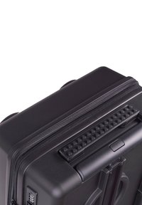 Black hard-shell suitcase features a textured surface, zip closure, sturdy handle, and patterned grip accents on top for easy handling.