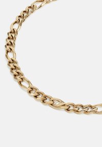 Collier en chaîne dorée avec des maillons entrelacés au fini lisse. Comprend un fermoir avec un détail de marque. Vue rapprochée.