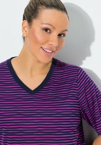 Camiseta de cuello en V con rayas moradas y azul marino, confeccionada en tejido suave. Cuenta con mangas cortas y un cuello de contraste.