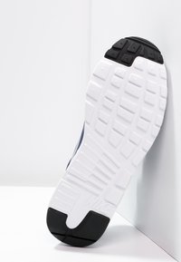 Nike-sneaker med en marinblå ovandel, vit mellansula och svart gummisula. Har en texturerad sula för grepp och stabilitet.