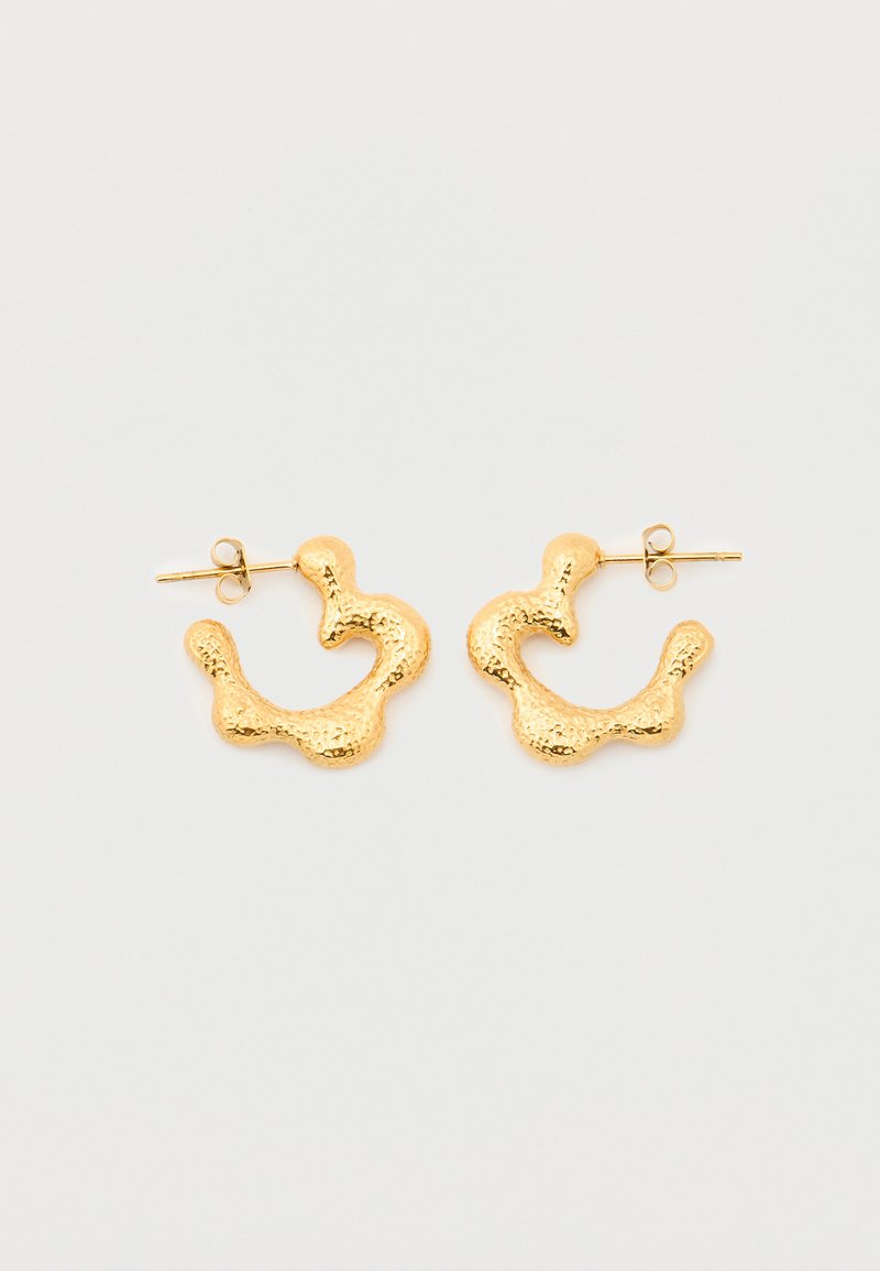 Κρίκοι σκουλαρίκια με υφή σε χρυσό τόνο, με ακανόνιστο, οργανικό σχήμα και κλεισίματα πεταλούδας, σε απλό λευκό φόντο.