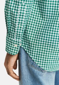 Groen en wit geblokt overhemd, van katoen, met knoopsluiting bij de mouwen, afgeronde zoom, gecombineerd met blauwe denim jeans. Gelaagd materiaal, casual ontwerp.