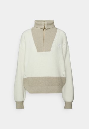 Pull en tricot blanc et beige avec un col haut zippé et manches longues, avec poignets et ourlet côtelés.
