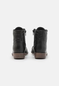 Botas de cuero negras hasta el tobillo con punta redondeada, que cuentan con un tacón de madera bajo y cremalleras laterales para un fácil calzado. Textura suave con detalles de diseño mínimos.