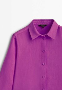 Purple linen shirt featuring a buttoned front, soft texture, pointed collar, and long sleeves. Buttons are matching in color.